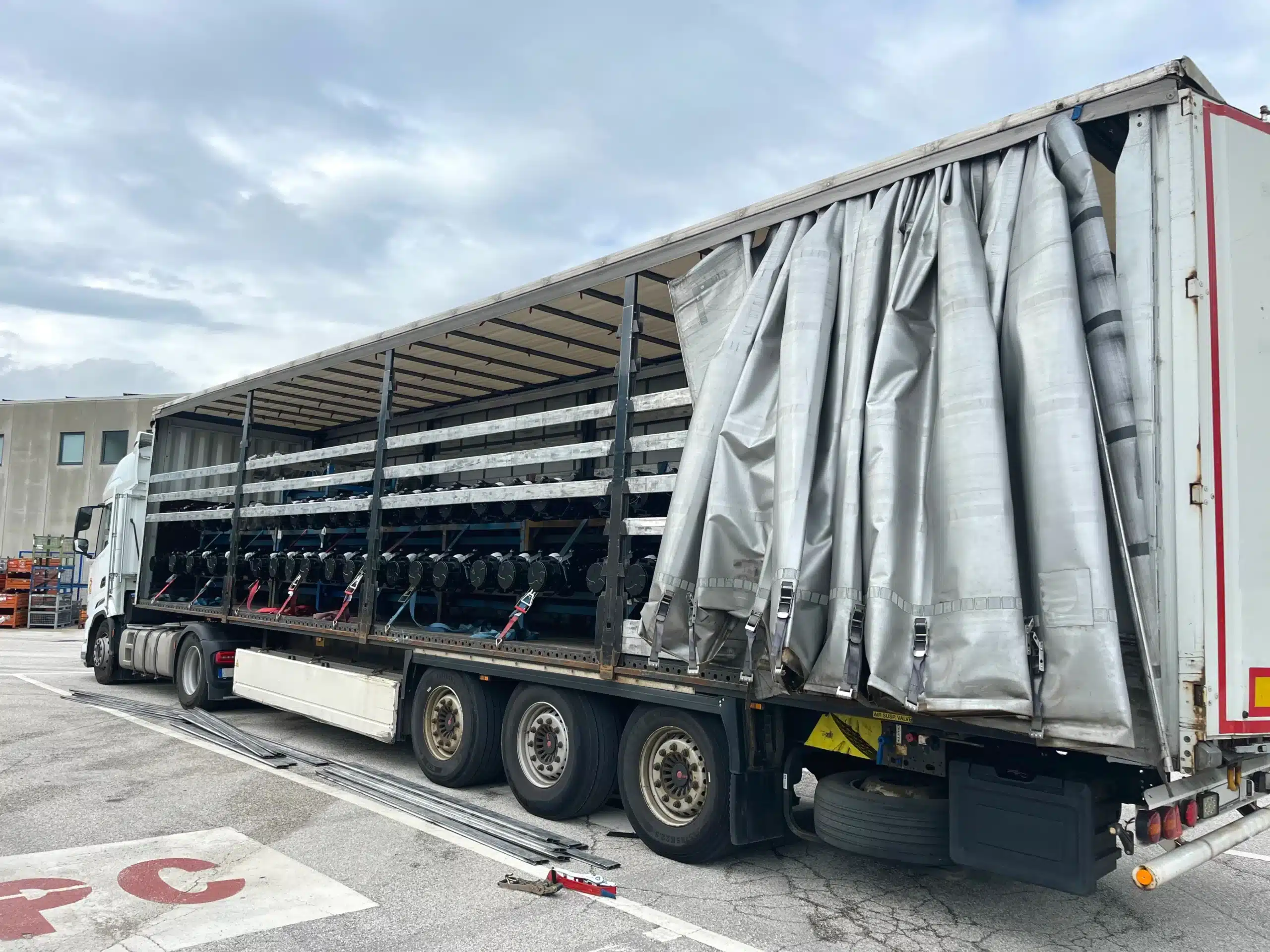 A large dry van trailer with its side curtain open reveals rows of mining rigs or computer servers loaded on shelves inside the trailer, parked on an outdoor lot. The innovative setup suggests RCT Logistics’ commitment to secure and efficient transportation of high-value technology equipment.